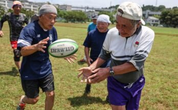 Un proche de cinq hommes plus âgés jouant du rugby dans un champ par une journée ensoleillée