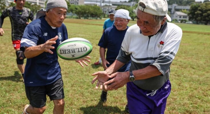 Un proche de cinq hommes plus âgés jouant du rugby dans un champ par une journée ensoleillée