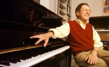 L'auteur-compositeur du chanteur Tom Lehrer pose pour un portrait assis à un piano.