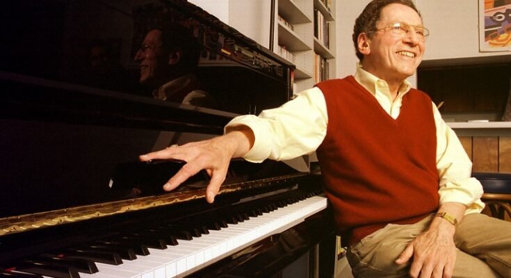 L'auteur-compositeur du chanteur Tom Lehrer pose pour un portrait assis à un piano.