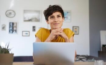 Portrait de femme souriante à la maison assis à table à l'aide d'un ordinateur portable
