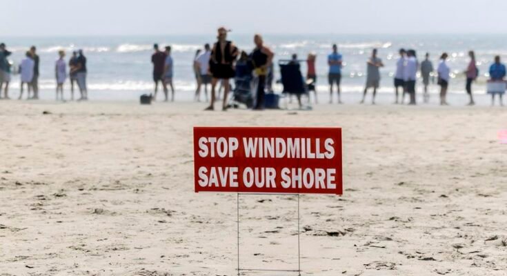 Un panneau rouge qui lit arrête des éoliennes, sauve notre pays installé sur la plage