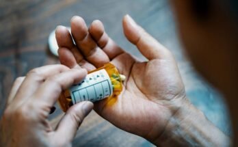 Fermement d'une main mâle tenant une bouteille de pilule, versant des médicaments à la main