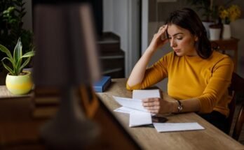 Jeune femme triant ses factures mensuelles et lut avec les finances