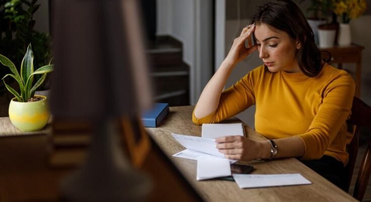 Jeune femme triant ses factures mensuelles et lut avec les finances