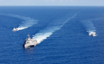 Un navire de bataille littoral de la flotte américaine navigue avec des navires prototypes autonomes.