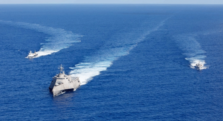 Un navire de bataille littoral de la flotte américaine navigue avec des navires prototypes autonomes.