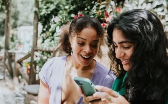 Deux jeunes femmes regardent le téléphone portable et sourient.