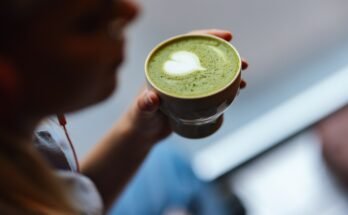 Gros plan d'une femme cachée tenant une tasse de thé matcha avec de la mousse verte