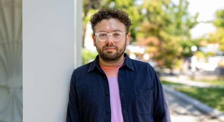 Portrait de Nikita Bezrukov, qui se tient à l'extérieur, appuyé contre un pilier