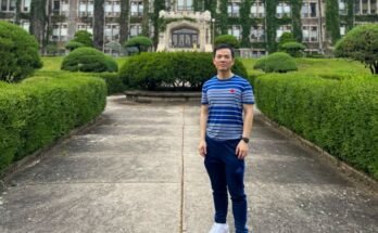 Zhicheng Lin se tenait sur un chemin à l'extérieur d'un bâtiment universitaire habillé par Efvy.