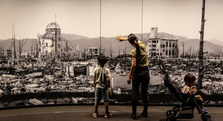 Une mère et deux enfants au Hiroshima Peace Memorial Museum voient un côté panoramique à grande échelle de demande de bombe nucléaire à Hiroshima