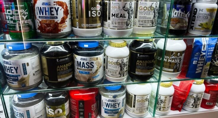 Rénits de poudre de protéines avec différentes marques et saveurs disposées sur les étagères en verre