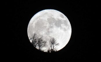 Une supermoon complète s'élève derrière une montagne.
